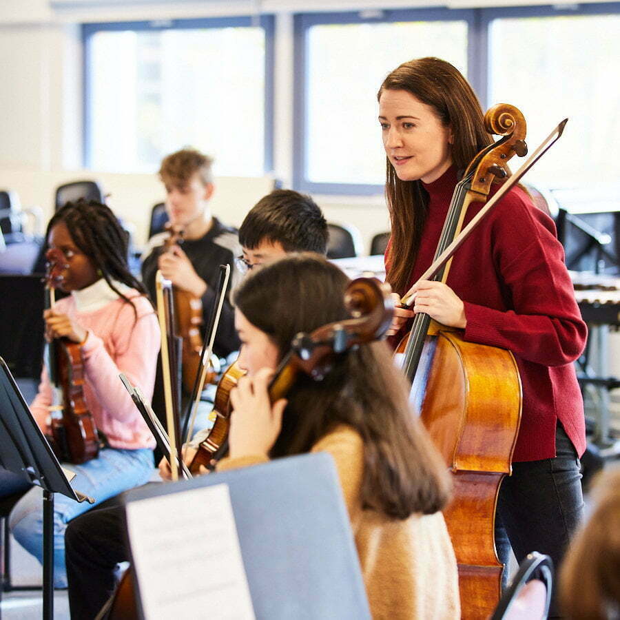 woman holding cello teaching young musicians